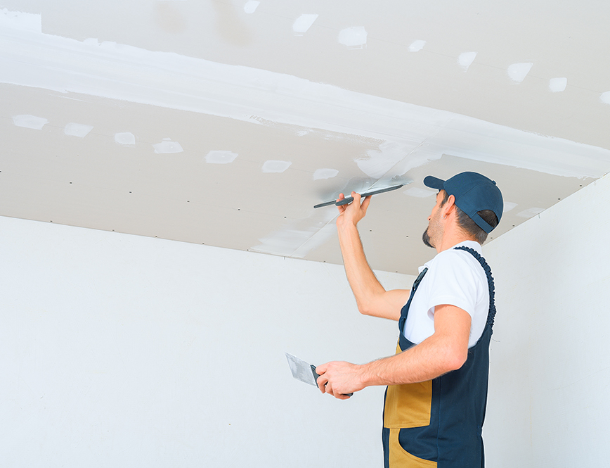 worker applies putty drywall ceiling